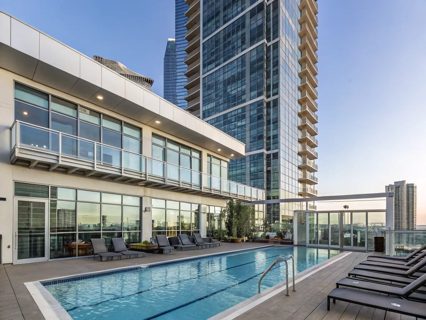 A modern apartment complex with a swimming pool and fitness center, located in a vibrant urban setting.
